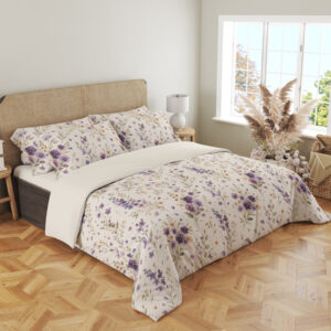 Angled full-bed view of ivory bedding with scattered purple and lavender pansies, small yellow flowers and delicate gray-green leafy stems, showing the pattern across the cover and pillows.