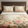 Front close view of ivory bedding with large blush-pink and peach flowers, cream blooms, airy white flower clusters and soft green leaves on the cover and matching pillows.