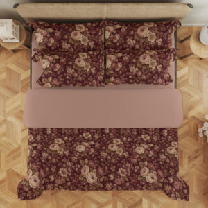 Overhead view of burgundy bedding with densely scattered cream and dusty-pink roses, tiny blossoms and muted olive leaves, with the design repeated on the pillows.