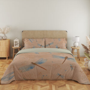 Full front view of peach bedding printed with blue-winged dragonflies with copper-brown bodies and fine scattered speckles beneath a beige headboard.