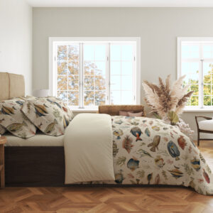 Side view of ivory bedding with small watercolor reef fish in blue, yellow, coral and gray swimming among delicate sea plants, showing the print across the draped cover.