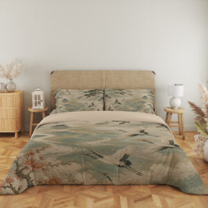Full front view of bedding printed with white cranes flying over pale teal waves, framed by dark branches and rust-colored blossoms beneath a beige headboard.
