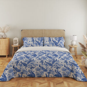 Full front view of ivory bedding with a dense indigo toile-style pattern of peacocks, flowering branches, leafy trees and garden foliage beneath a beige headboard.