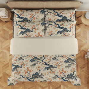 Overhead view of cream bedding printed with twisting indigo branches, soft blue foliage and clusters of small coral blossoms, with the design repeated on the pillows.