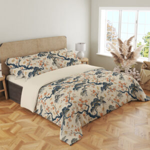 Angled full-bed view of cream bedding printed with twisting indigo branches, soft blue foliage and clusters of small coral blossoms, showing the pattern across the cover and pillows.