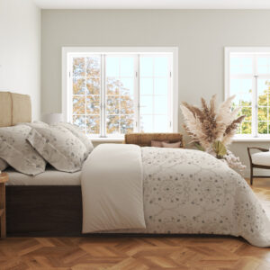 Side view of ivory bedding with pale-gray floral medallions, tiny dotted flowers and fine scalloped lace-like printed borders, showing the print across the draped cover.