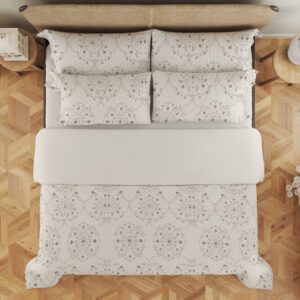 Overhead view of ivory bedding with pale-gray floral medallions, tiny dotted flowers and fine scalloped lace-like printed borders, with the design repeated on the pillows.