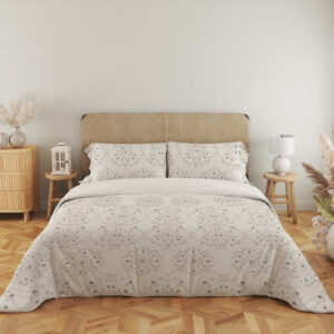 Full front view of ivory bedding with pale-gray floral medallions, tiny dotted flowers and fine scalloped lace-like printed borders beneath a beige headboard.