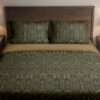 Front close view of dark juniper-green bedding with repeating fine ochre geometric arches, elongated leaf shapes and wheat-like stems on the cover and matching pillows.