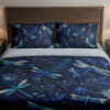 Front close view of navy bedding printed with turquoise and pale green dragonflies among blue flowers and fine botanical sprigs on the cover and matching pillows.