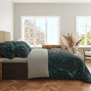 Side view of deep teal bedding printed with winding pale blue streams, dense green foliage, tiny red flowers and crescent moons, showing the print across the draped cover.