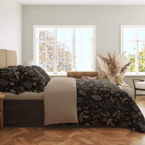 Side view of charcoal bedding printed with a dense repeat of taupe mushrooms, fern fronds, leaves and small woodland flowers, showing the print across the draped cover.
