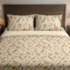 Front close view of ivory bedding with small ochre fern fronds, muted green leafy sprigs, pale flowers and tiny crescent moons on the cover and matching pillows.