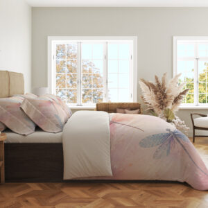 Side view of bedding printed with translucent pink, lavender and blue dragonflies over a soft peach, cream and pink watercolor ground, showing the print across the draped cover.