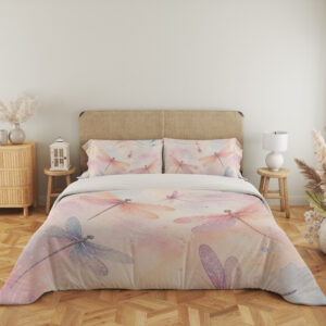 Full front view of bedding printed with translucent pink, lavender and blue dragonflies over a soft peach, cream and pink watercolor ground beneath a beige headboard.