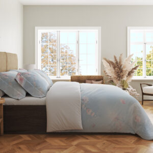 Side view of pale blue bedding with scattered pink petals and soft blossom sprigs across the draped cover.