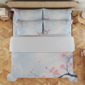 Overhead view of pale blue bedding printed with delicate pink blossoms on dark branches and scattered petals around an open misty center, with the design repeated on the pillows.
