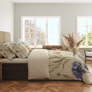 Side view of floral bedding, showing blue cornflowers, fine green stems and part of a red lily on the draped cream cover.