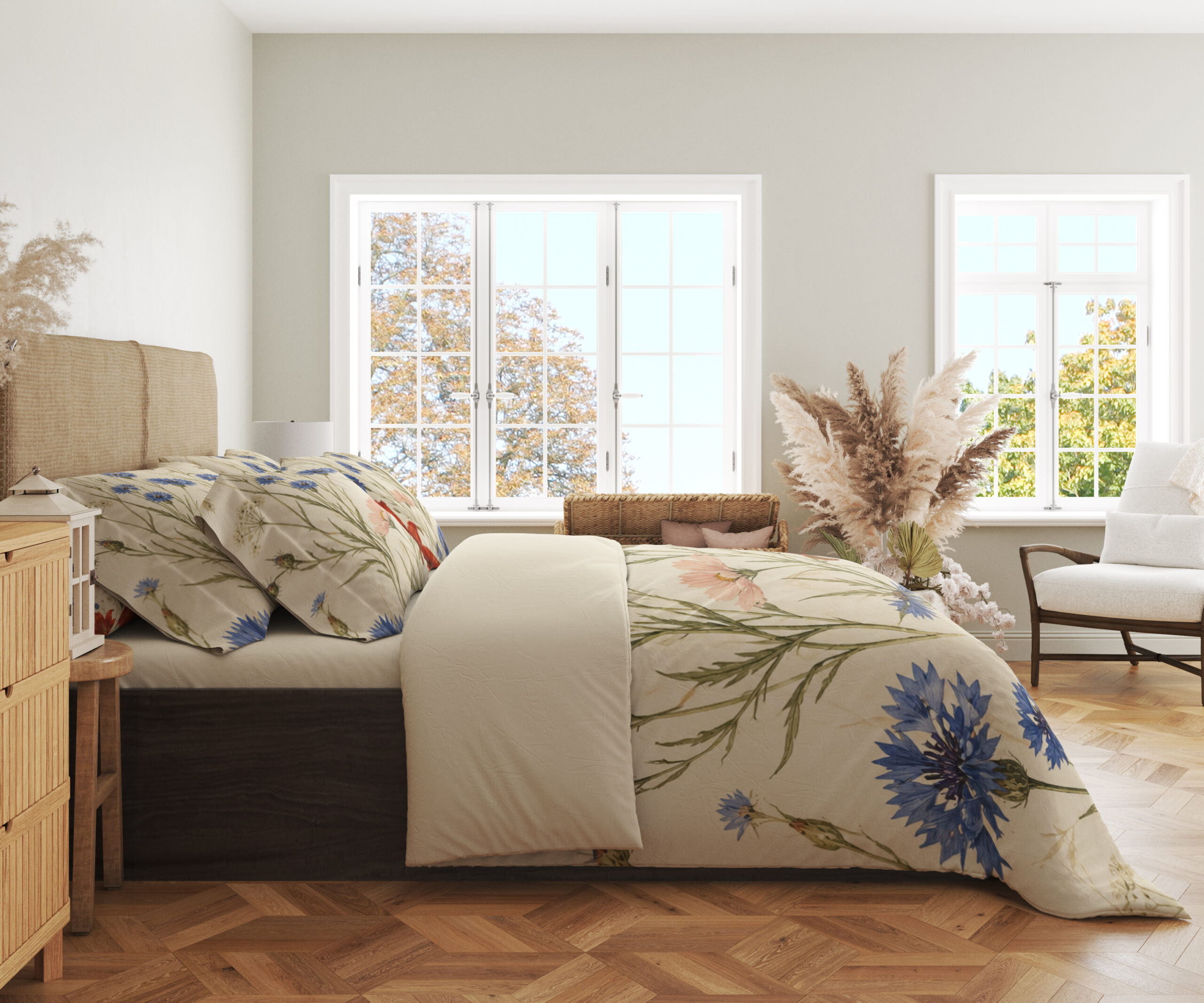 Side view of floral bedding, showing blue cornflowers, fine green stems and part of a red lily on the draped cream cover.
