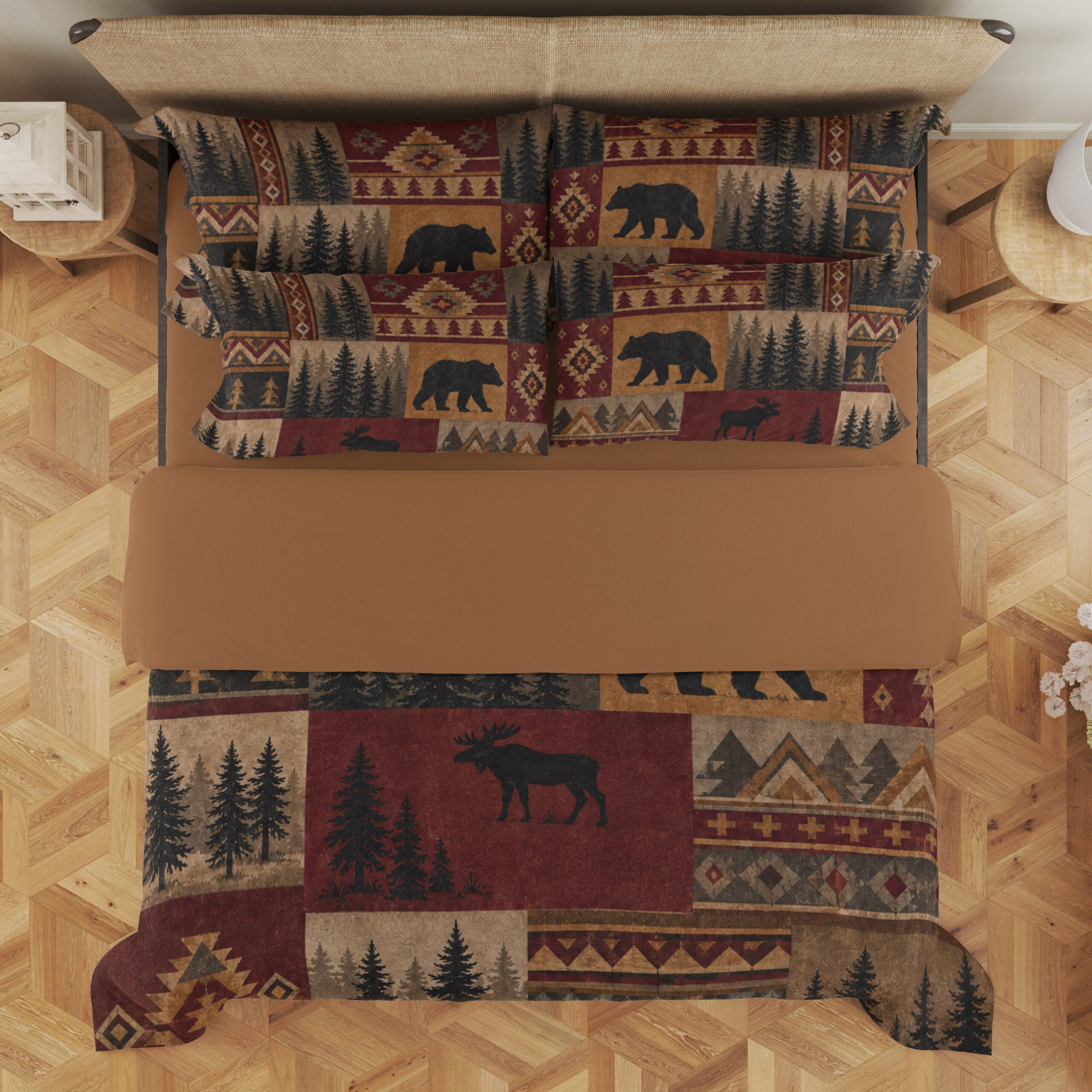 Overhead view of bedding printed with burgundy, ochre and tan patchwork panels of black bears, moose, pine trees and geometric borders, with the design repeated on the pillows.