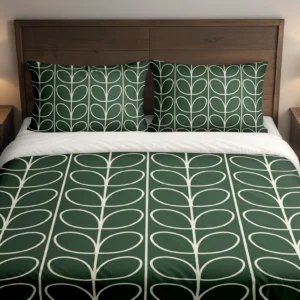 Forest-green bedding with ivory looping leaves running down the duvet and matching pillows, shown close up from the foot of the bed.