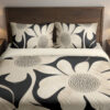 Front close view of charcoal bedding printed with oversized ivory flowers, curved petals and finely dotted centers on the cover and matching pillows.