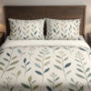 Front close view of ivory bedding with slender upright stems and simple pointed leaves in muted teal, sage and olive on the cover and matching pillows.