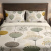 Front close view of ivory bedding printed with widely spaced sage, mustard and gray rounded seedheads on slender stems on the cover and matching pillows.