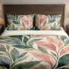 Front view of pointed blush, sage, deep green and blue-gray leaves with ochre accents on a cream duvet cover and matching pillowcases against a dark wooden headboard.