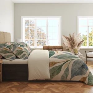 Side view of branching sage, deep green and blue-gray leaves with blush and ochre accents on a cream duvet cover and matching pillowcases in a windowed room.