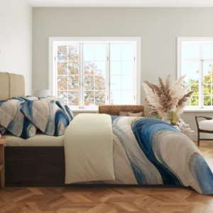 Side view of the ivory and blue ribbon duvet cover with gold-colored accents and matching pillowcases in a bright room with large windows.