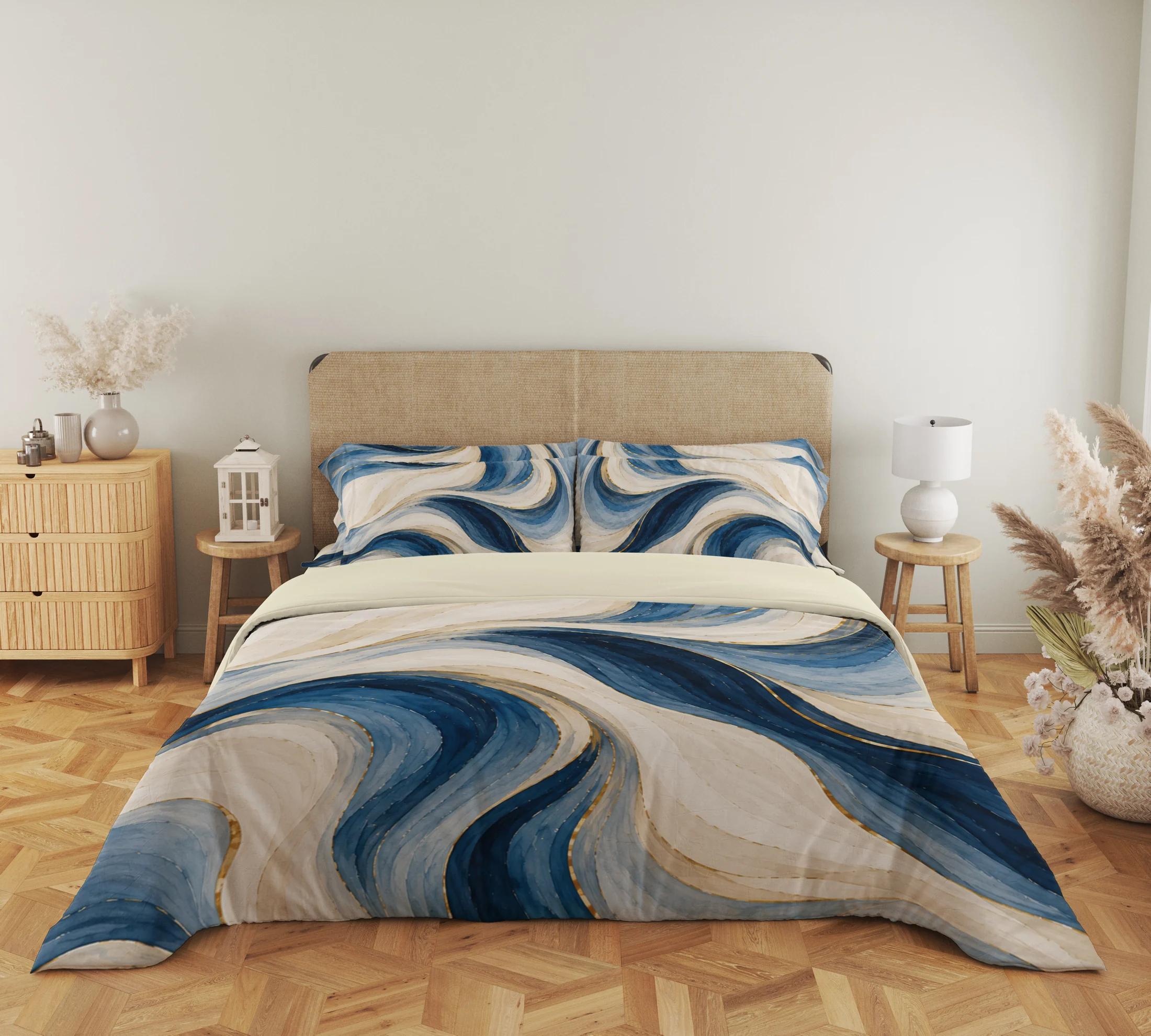 Wide front view of the ivory and blue flowing ribbon duvet cover and matching pillows, with gold-colored accents, a woven headboard, lantern and bedside lamp.