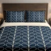 Navy bedding with cream oval leaf outlines arranged in vertical columns across the duvet and pillows, viewed closely from the front.