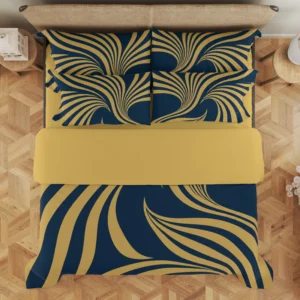 Overhead view of navy and gold-colored ribbon-fan bedding with a wide gold-colored fold and four styled printed pillows on a wood floor.