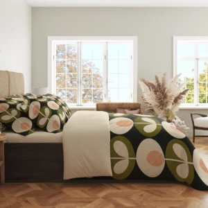 Side view of a charcoal duvet with large peach-centered cream flowers and olive medallions along its hanging edge beside a cream fold.