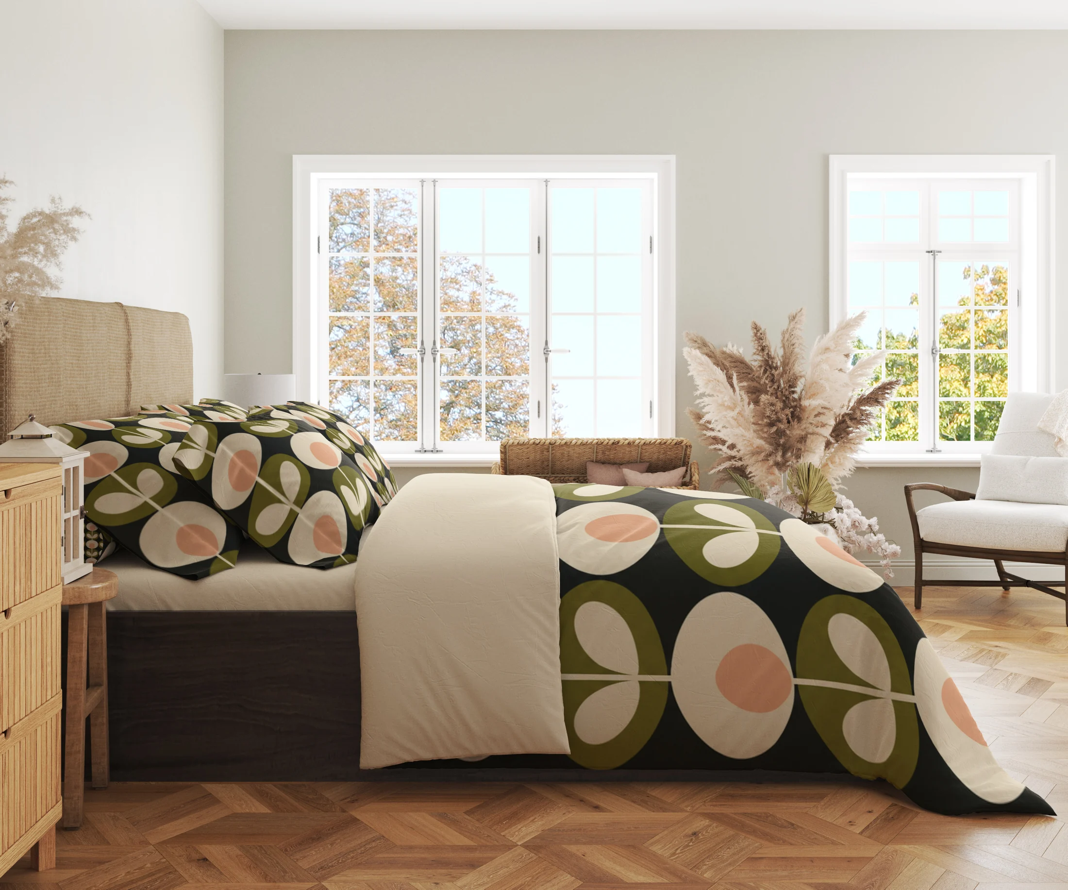 Side view of a charcoal duvet with large peach-centered cream flowers and olive medallions along its hanging edge beside a cream fold.