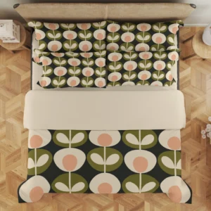 Overhead view of charcoal bedding with alternating cream flowers and olive paired-leaf motifs below a broad cream fold and across layered pillows.