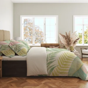 Side view of pastel green tropical leaves, blush foliage and pale yellow fronds on a cream duvet cover and matching pillowcases in a bright windowed room.