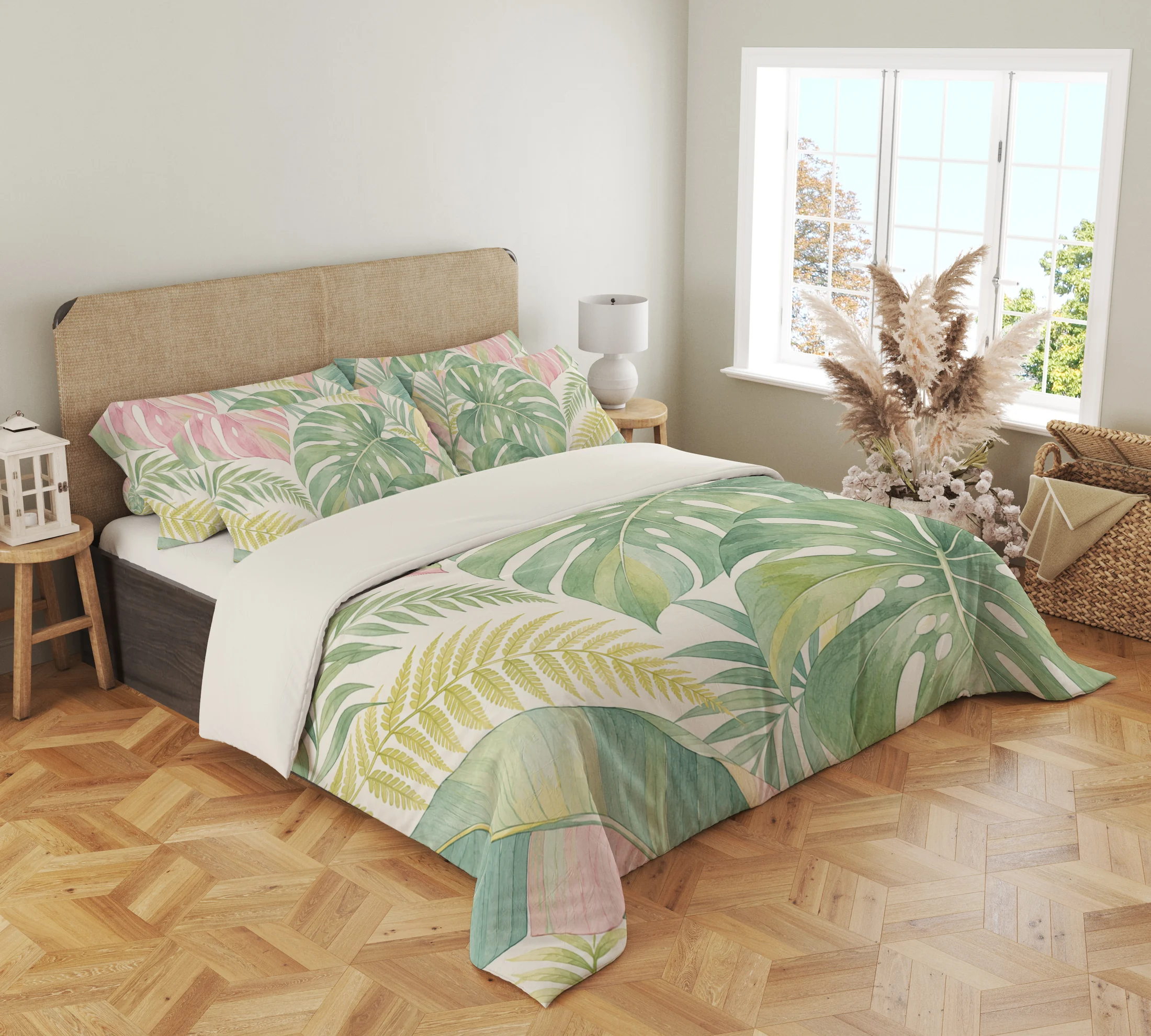 Three-quarter view of sage split leaves, blush tropical foliage and pale yellow fronds on a cream duvet cover and matching pillows beside a window.