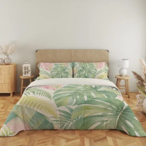Wide front view of oversized sage and blush tropical leaves with pale yellow fronds on a cream duvet cover and matching pillows, beside a lantern and lamp.