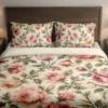 Front view of a cream duvet cover and matching pillows with layered rose, coral and peach peony-style blooms and olive foliage.