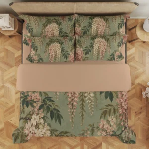 Overhead view of a sage duvet cover and matching floral pillows, showing cream and dusty rose blossom trails among green leaves beneath a peach-beige fold.
