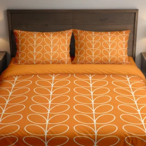 Bright orange bedding with fine ivory leaf loops across the duvet and pillows, shown from the front with a plain orange folded edge.