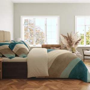 Side view of teal, seafoam and sandy curved-band bedding with printed pillows and a wide cream fold in a bright windowed room.