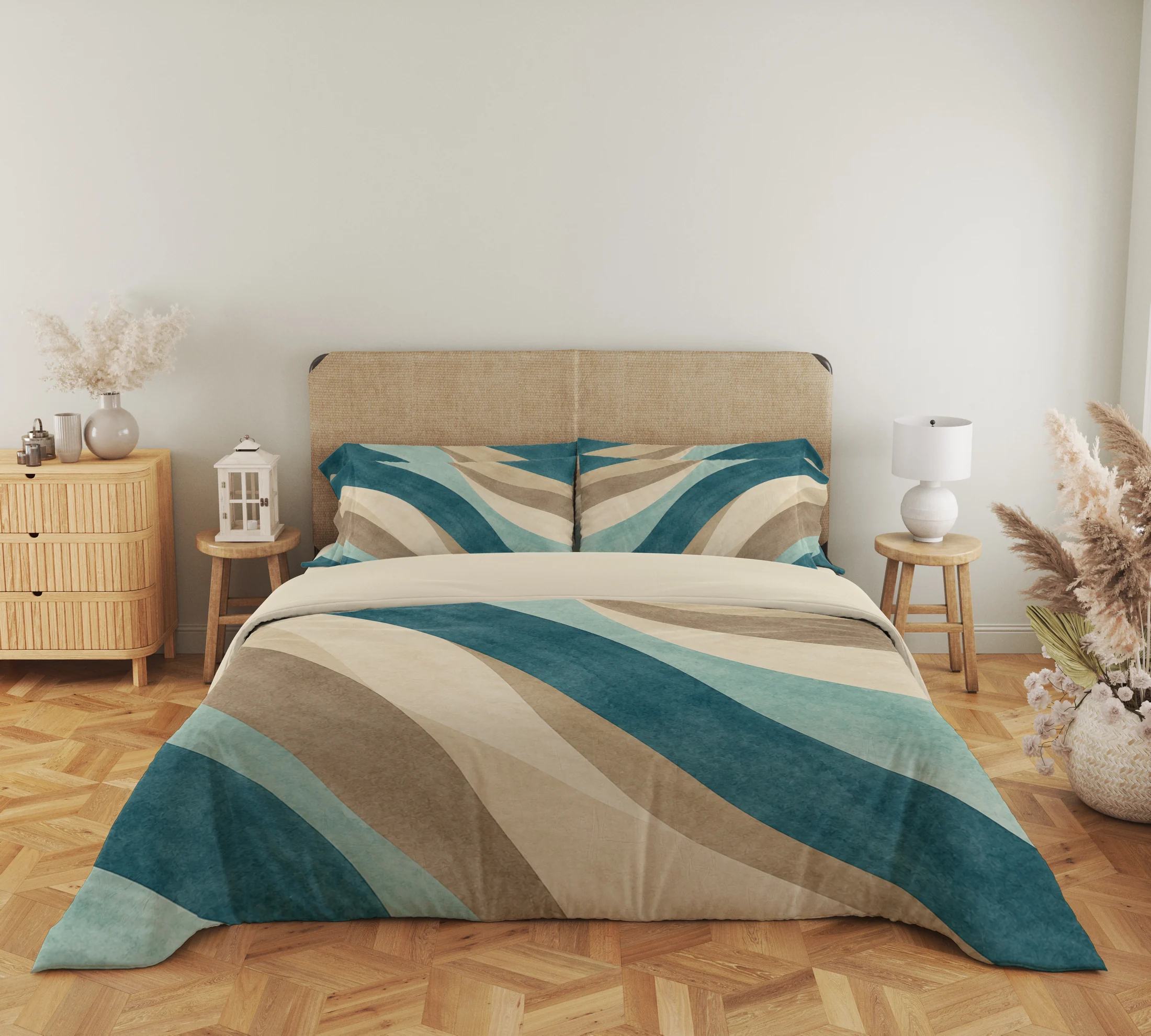 Close frontal view of teal, seafoam and sand curved-band bedding with two printed pillows and a cream fold above the draped duvet.